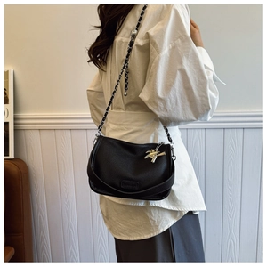 Detail of black lychee leather crossbody bag with silver chain strap and horse charm