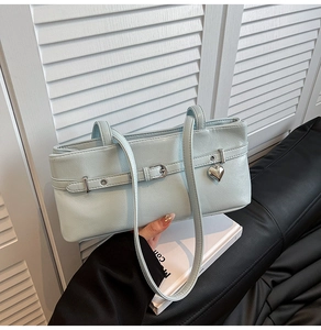 Detail of light blue faux leather texture with silver heart pendant on a shoulder bag