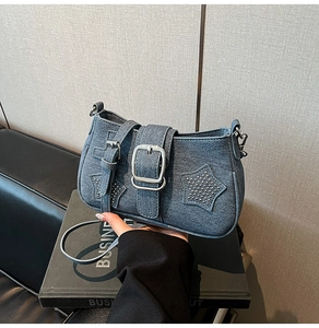 Detail view of denim shoulder bag featuring silver buckle and sparkling star accents