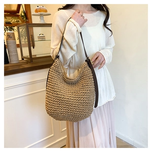Gros plan sur la texture du sac cabas en paille avec bandoulière en cuir marron