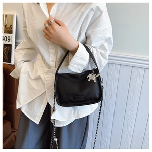 Detail of black lychee grain leather handbag with silver chain strap and pegasus charm