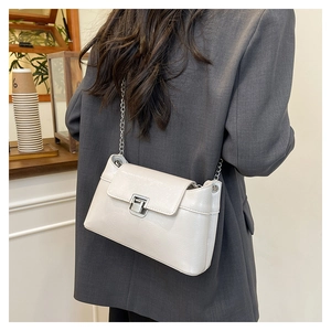 Petit sac en cuir verni blanc avec chaîne porté sur un blazer gris élégant
