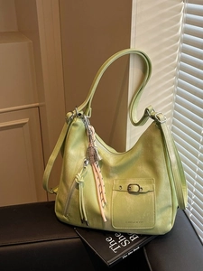 Light green leather hobo bag with metal buckle and tennis racket pendant on black bench