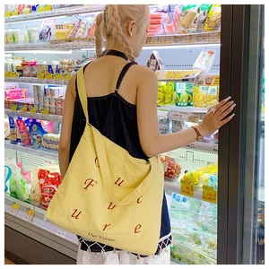 Φωτογραφία lifestyle κίτρινης νάιλον τσάντας tote σε σούπερ μάρκετ με γράμματα Future
