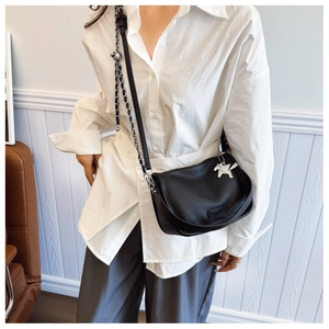 Close-up of black litchi pattern crossbody bag with silver chain and horse pendant