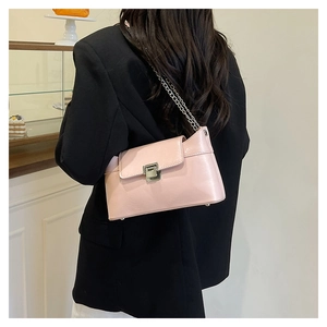 Petit sac rose à chaîne avec fermoir métallique porté à l'épaule dans un décor moderne