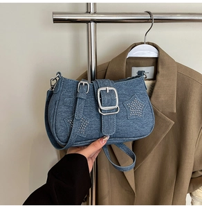 Close-up of blue denim shoulder bag featuring sparkling rhinestone stars and a metal buckle