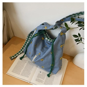 Detail of light blue denim canvas bucket bag with yellow flower embroidery and drawstring