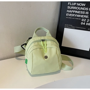 Close-up of mint green nylon bag featuring adjustable straps and dual zipper pull cords