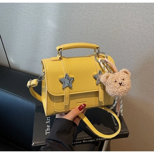 Détails du cuir grainé jaune du sac avec étoiles argentées et breloque peluche design