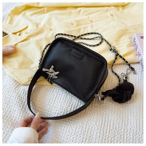 Close-up of black lychee grain leather chain bag with silver bird-shaped metal pendant