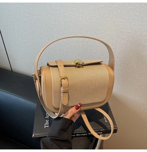 Close-up of beige leather and woven fabric shoulder bag with golden half-moon lock