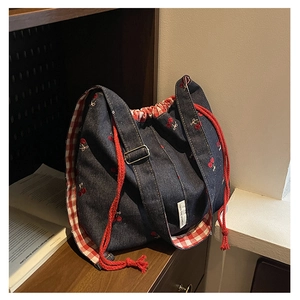 Detail of denim bucket bag with cherry embroidery, red drawstring and checkered lining