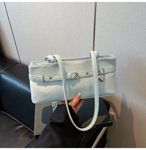 Detail of light blue lychee leather shoulder bag with buckle and heart pendant
