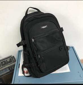 Détail du sac à dos noir en nylon avec compartiments multiples, poche filet et boucles