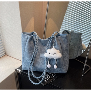 Detail of light blue floral jacquard tote bag with woven handles and cloud pendant