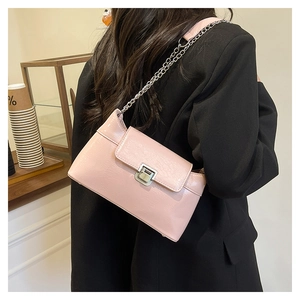 Détail du sac à chaîne rose brillant sur un blazer noir avec fermoir rotatif argenté