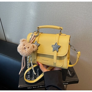 Détail du sac à main en cuir jaune avec étoiles en métal et breloque ourson