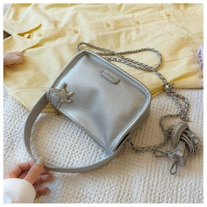 Detailed macro of silver pebble textured square bag with metal charm and chain strap