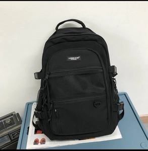 Vue détaillée du sac à dos noir avec poche en filet frontale et broderie de la marque