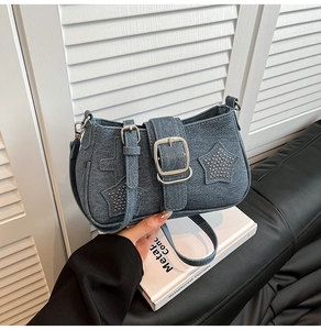 Detail of blue denim shoulder bag with silver buckle, star studs and cross texture