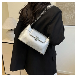 Détail du sac à main argenté avec gaufrage crocodile, chaîne en métal et fermoir