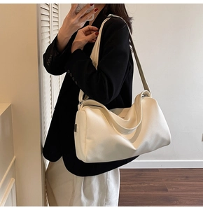 Side view of white textured shoulder bag shown on model in a modern interior setting