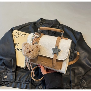Détail du sac à main bicolore avec pièce en étoile et breloque ours sur cuir