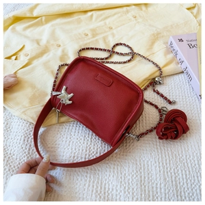 Detail of red pebbled leather bag with silver bird charm and dual shoulder straps