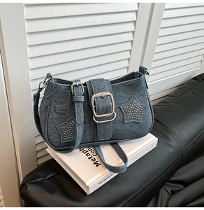 Detailed close-up of blue denim shoulder bag with star rivets and silver buckles