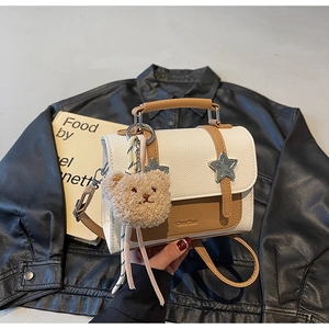Détail du sac bicolore avec accent d'étoile métallique et décoration de charme d'ours
