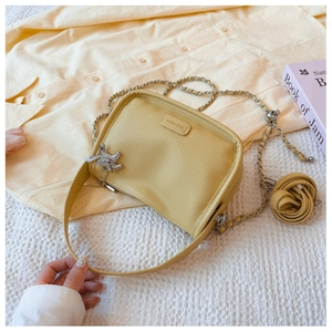 Detail of yellow lychee leather bag with silver puppy charm and leather rose decoration