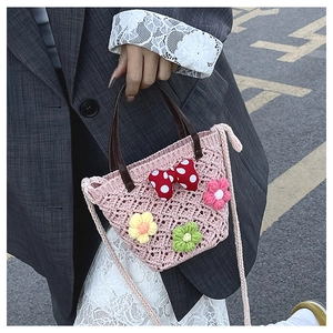 Close-up of pink crochet bucket bag with floral accents and a red polka dot bow