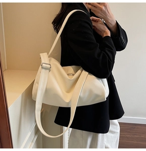 Detail of hobo bag in beige pebble grain leather with wide shoulder strap and metal buckle