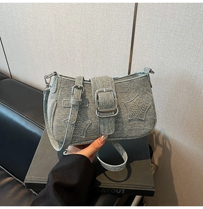 Detail of vintage denim crossbody bag with silver star rivets and buckle strap