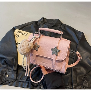 Détail du sac bandoulière rose avec clous en étoile et breloque ours en peluche