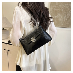 Détail du sac bandoulière noir texture crocodile avec chaîne et boucle argentées