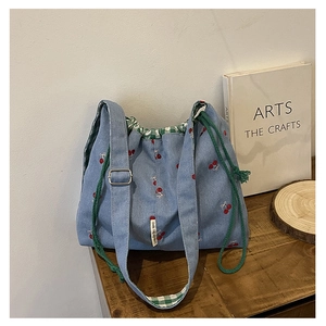 Detailed shot of cherry print denim tote bag with green drawstring and checkered lining
