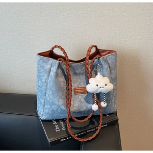 Detail of light blue floral embossed denim tote bag with woven handles and cloud charm