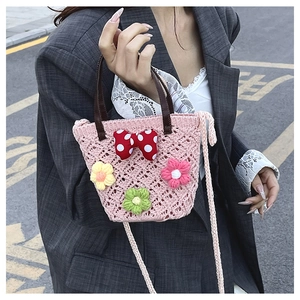 Close-up of pink crochet bucket bag with 3D floral details and red polka dot bow