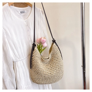 Détail du sac seau en paille beige tissée avec bandoulière réglable en cuir marron
