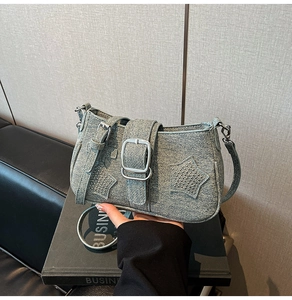 Detailed macro view of denim shoulder bag with silver buckle and star rivet patches
