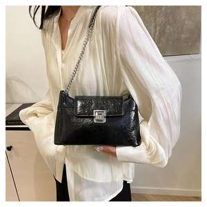 Détail du sac bandoulière en cuir craquelé noir avec chaîne argentée et boucle carrée