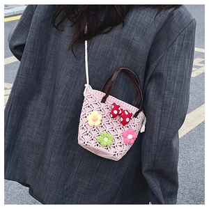 Detail view of pink crochet mini bucket bag with colorful 3D flowers and red bow accent
