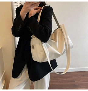 Side view of white faux leather tote bag with square metal buckle on shoulder strap