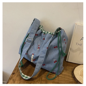 Detail of blue denim tote bag with cherry embroidery and green checkered lining