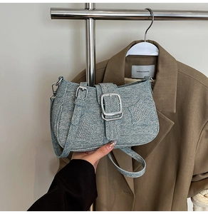 Detail of blue denim shoulder bag with silver buckle and rhinestone star accents