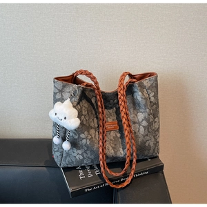 Detail view of floral print canvas tote bag with orange braided handles and cloud pendant