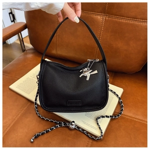 Close-up of black lychee grain leather handbag with silver pegasus charm and chain strap