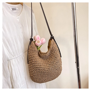 Détail d'un sac seau en paille fait main avec bandoulière en cuir marron et texture tissée